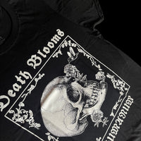 Angled view of black unisex T-shirt featuring gothic floral border with hummingbird drinking from skull flower design. 'Death Blooms' and 'INHUMANUM' printed in white – INHUMANUM dark art streetwear