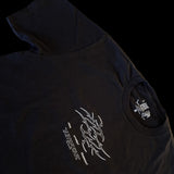 Angled view of black t-shirt with neotribal “Fallen Angel” flame logo and Latin microtext reading “Ave Dominum Inferni” – gothic streetwear
